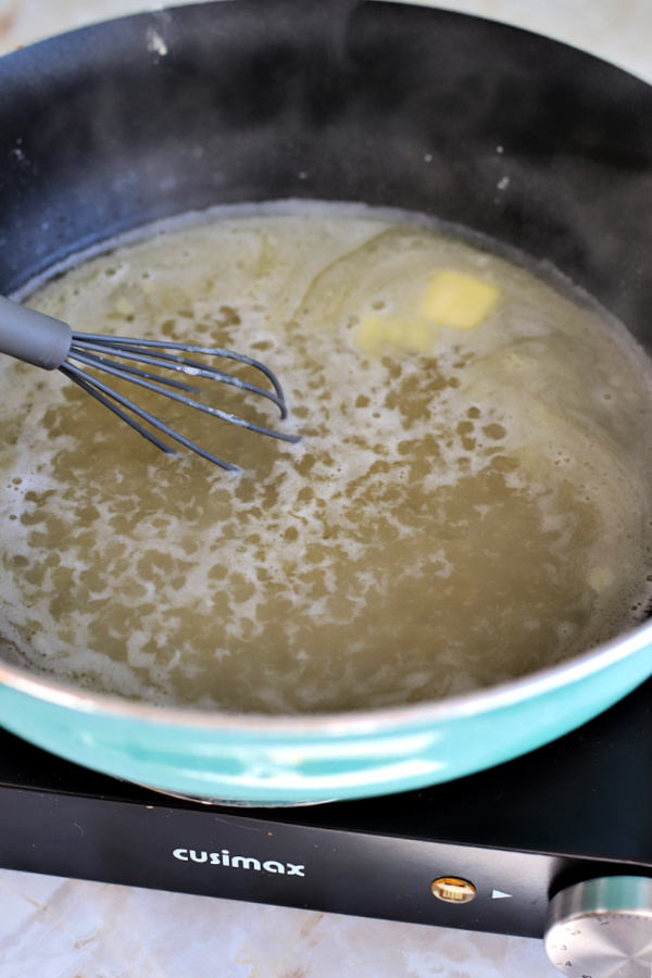 Simmering broth lemon and butter for chicken francese.