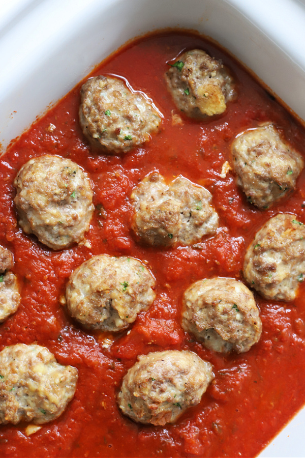 Adding ground beef favorite meatballs to tomato sauce to simmer