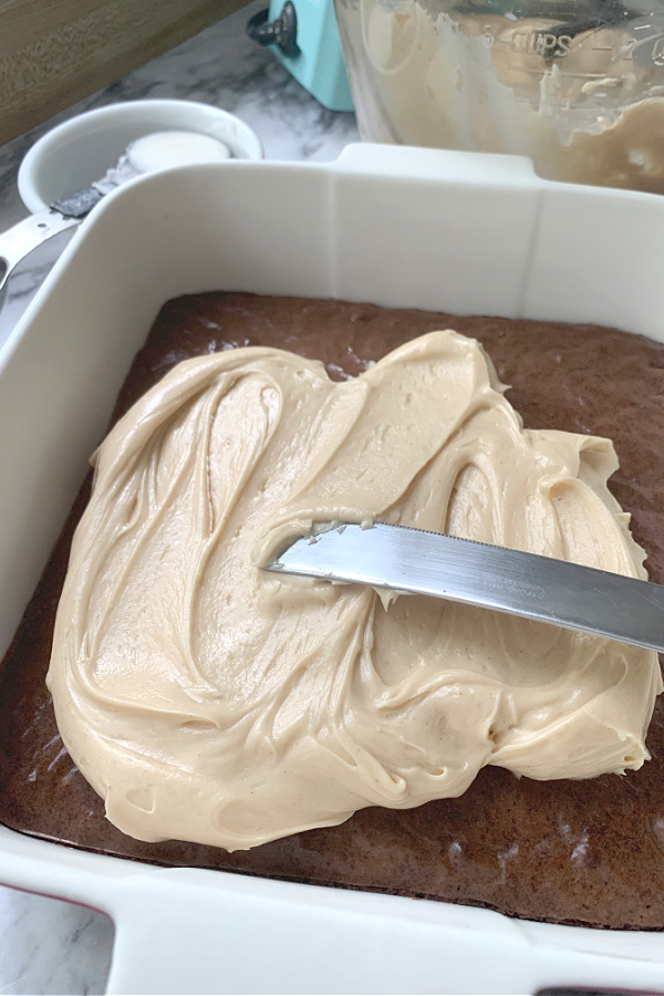 Spreading creamy frosting on Peanut Butter Frosted Brownies.