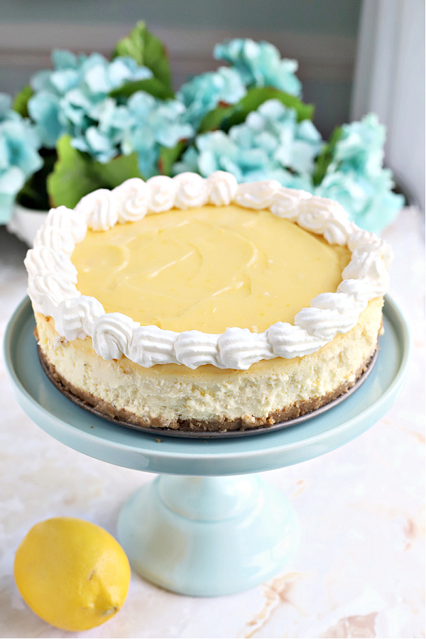 Piping whipped cream over Philadelphia cream cheese cheesecake with lemon curd.