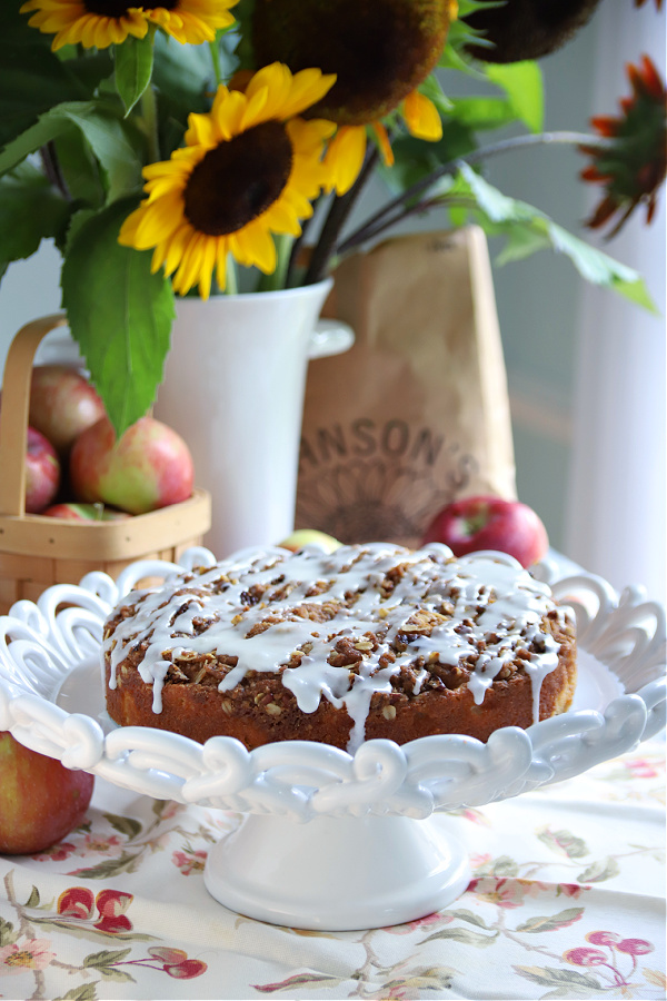 An easy recipe for apple coffee cake with an oat and pecan crumbly topping and a white glaze. It is a lovely autumn dessert or snacking time treat. 