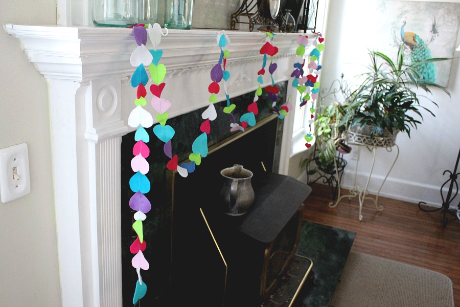 Easy Valentine's Day garland made by sewing felt hearts together. Hang hearts overflowing garland on the mantle, a window or wherever happy hearts are wanted.