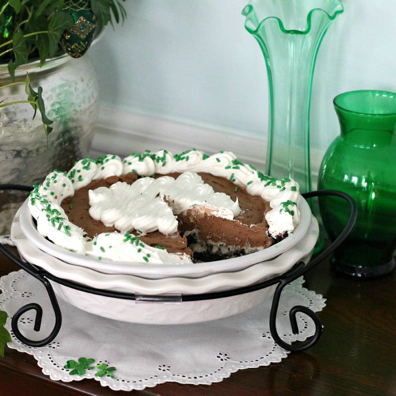 A layer of ice cream with chocolate chips and a layer of chocolaty mousse in a chocolate graham cracker pie crust make up this delicious Frozen Minty Mousse Pie. A great dessert recipe for St. Patrick's Day.