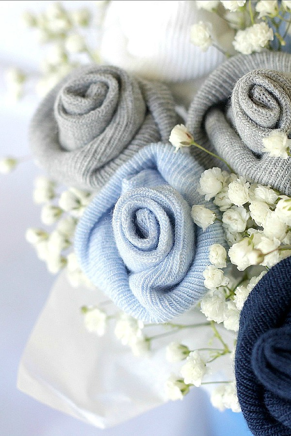 Celebrate a new baby with a sweet baby sock bouquet. Easy how-to tutorial to create a sweet shower decoration or gift for a new mom with little rosebuds from rolled baby socks. 