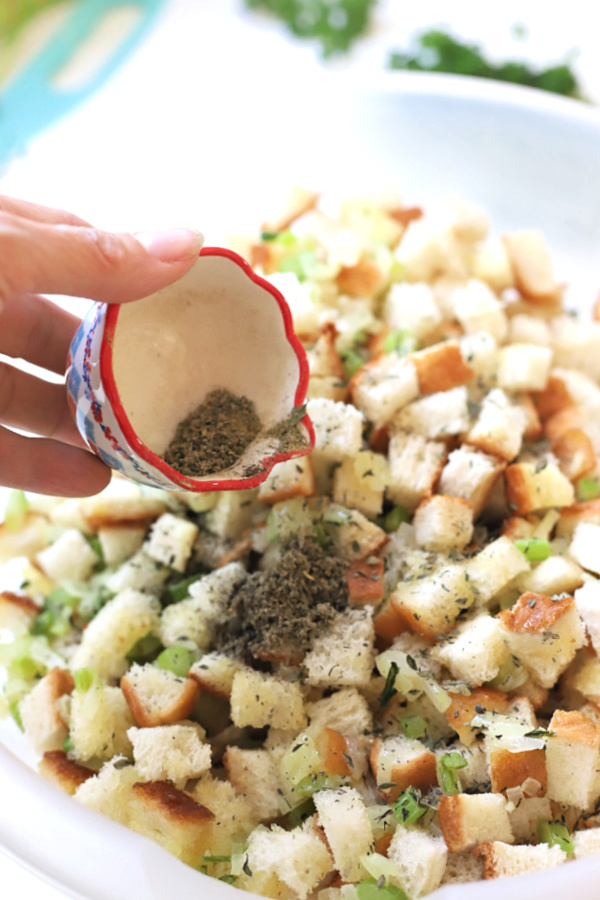 adding herbs to bread cubes