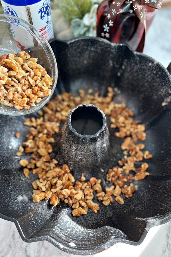 Adding chopped walnuts to prepared Bundt pan for Rum Cake recipe.