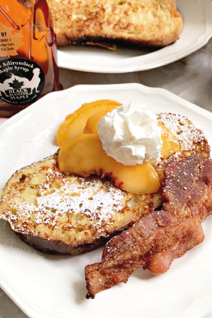 Homemade French toast with maple syrup, peaches and whipped cream