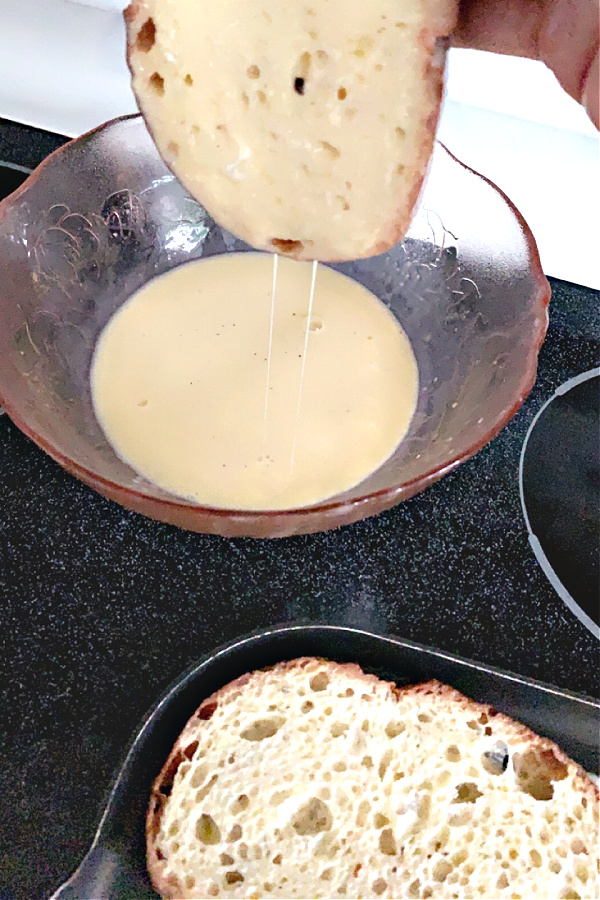 dipping bread into egg mixture for French toast breakfast