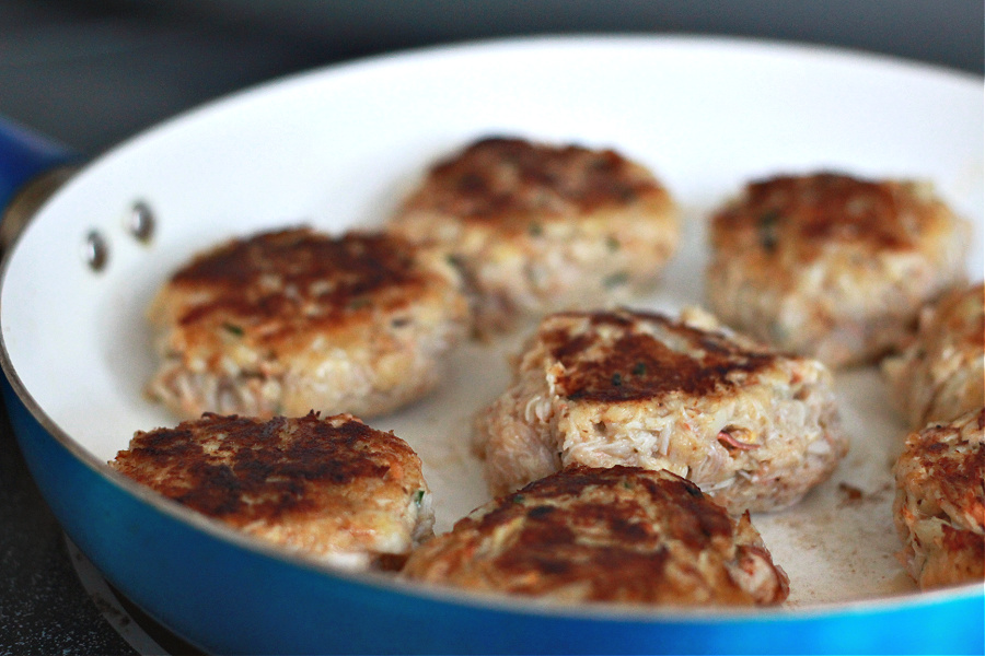 Frying classic crab cake patties in butter in skillet.