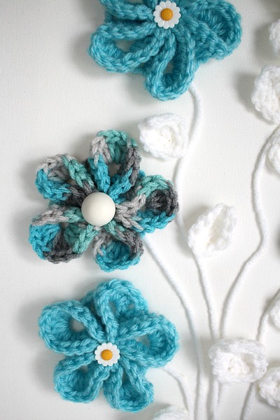 Pretty crochet flowers for all kinds of projects. Wall art or embellishing hats, beanies and bags. Easy to follow video tutorial.