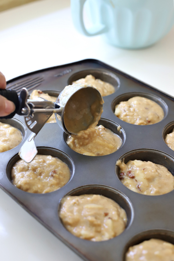 Adding pear, banana and walnut muffin batter to muffin tin.