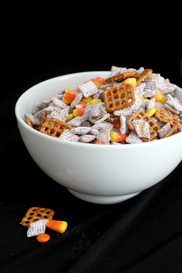 Make a batch of crunchy, crispy, salty and sweet Autumn Puppy Chow for Halloween. Easy recipe for Chex mix Muddy Buddies with chocolate, peanut butter, pretzels and candy corn for a frightfully delicious party treat!