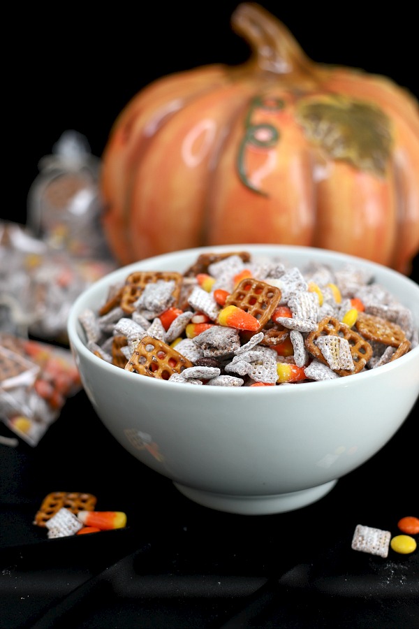Fun to eat, fun to give and fun to receive, autumn puppy chow is a great Halloween treat! Chex cereal mixed with chocolate and peanut butter then tossed with confectioners sugar is easy and crazy good! Toss in pretzels and candy corn for a frightfully delicious party snack. 