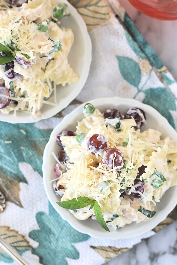 Easy recipe for creamy chicken pasta salad, made with bow tie pasta, chicken, Parmesan cheese, grapes, veggies and basil, is a perfect potluck food, tasty lunch entrée, cookout side dish or a tasty dinner. 