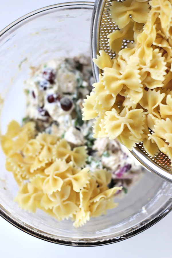 Make a big bowlful of creamy chicken pasta salad for dinner, lunch, potluck or cookout side dish. Easy recipe full of chicken, Parmesan, grapes and veggies with a fresh burst of basil.