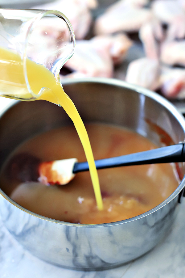 Adding orange juice to the sticky chicken wings glaze.