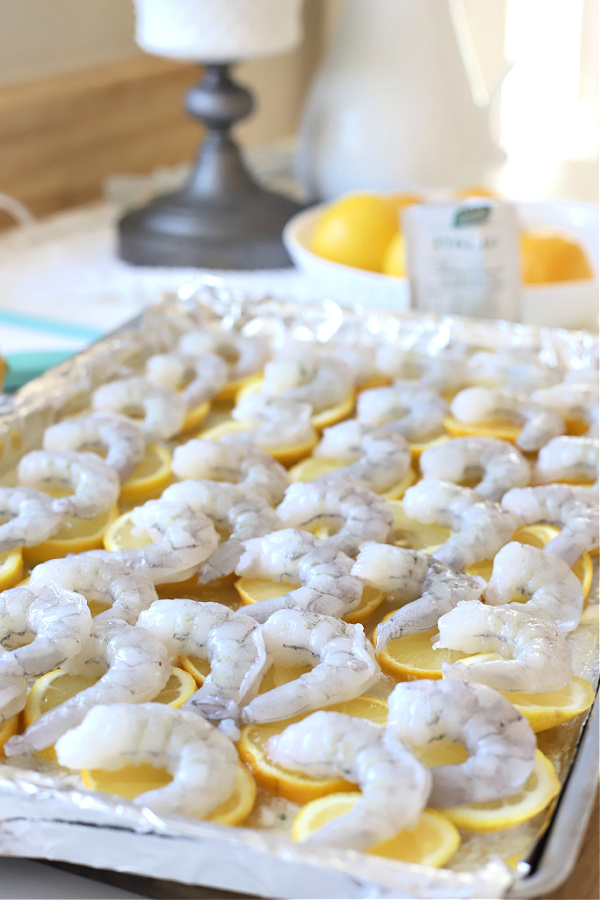 Topping sliced lemons with shrimp for one pan lemon shrimp recipe.