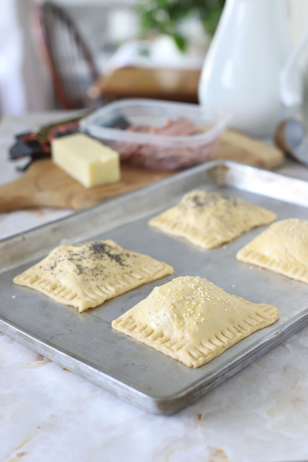 adding poppy and sesame seeds to ham and cheese crescent hand pies