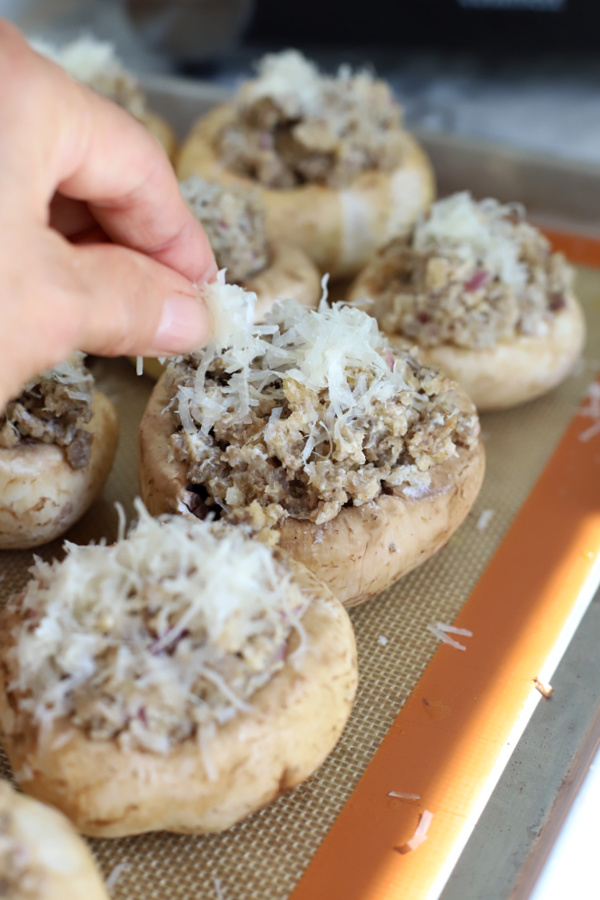 Sprinkling Parmesan cheese to tops of sausage stuffed mushrooms before baking