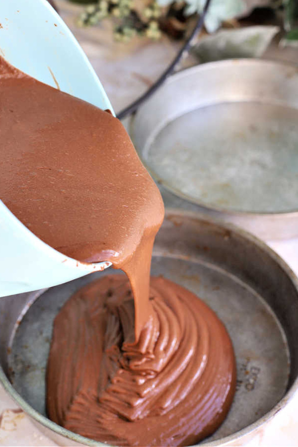 Pouring chocolate mocha cake batter into greased 8-inch pans.