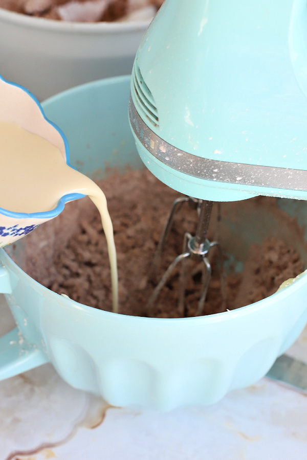 Adding milk to the fluffy chocolate frosting recipe.