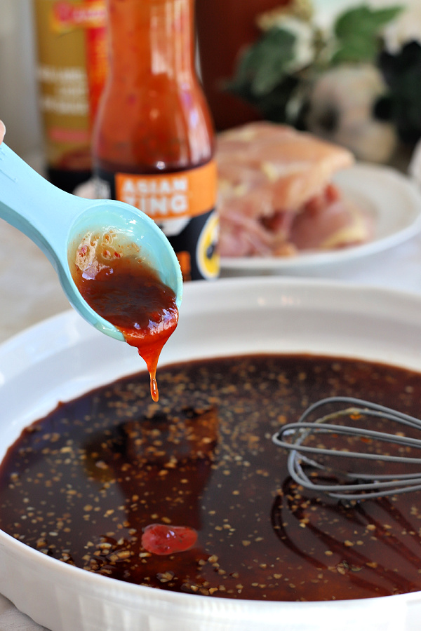 Adding Asian Zing chili pepper sauce to marinade for air fryer chicken thighs.