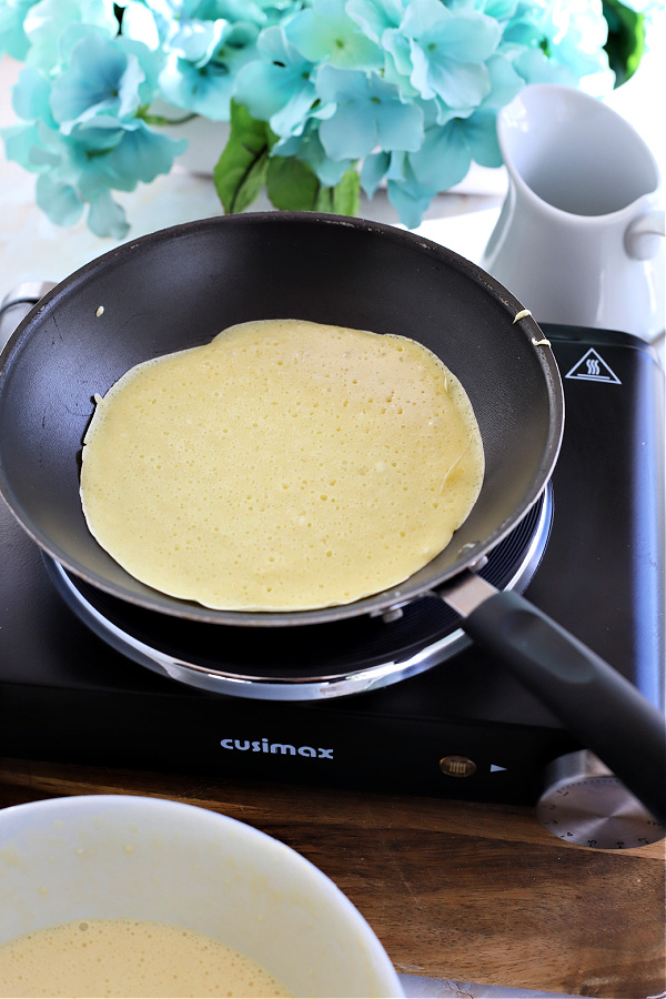 Cooking the crepes in a small skillet for manicotti pasta.