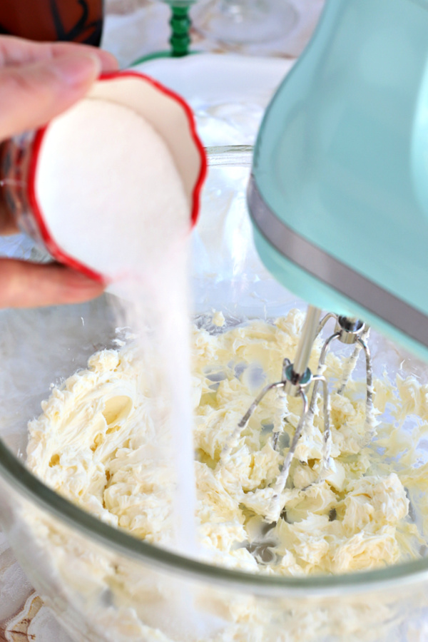 Adding sugar to cream cheese for making Chocolate Mint Cheesecake Parfait.