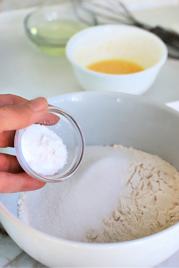 Adding baking powder to the dry ingredients for making basic muffins.