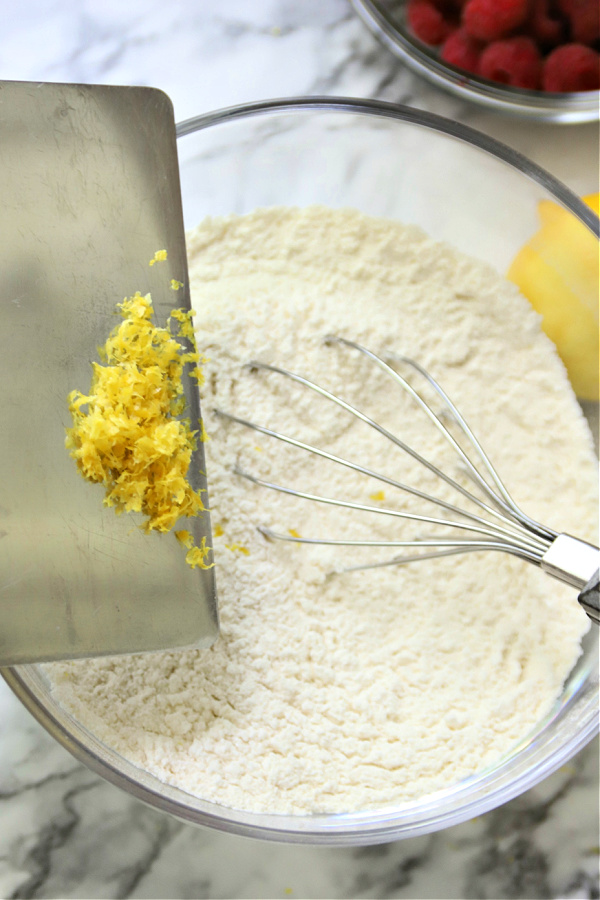 Adding lemon zest to batter for raspberry very berry muffins recipe.