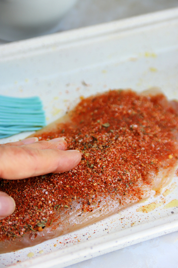 patting on herbs and spices for baked blackened tilapia fish