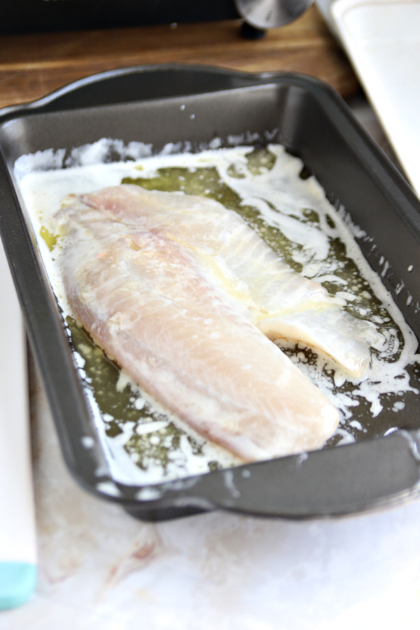 dipping fish into butter for blackened tilapia.