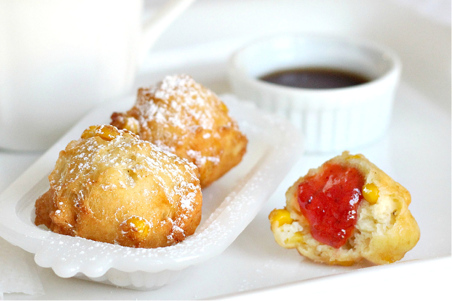 Old fashioned corn fritters with strawberry jam and confectioners sugar.