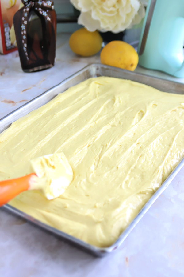 spreading the lemon sheet cake batter into prepared pan.