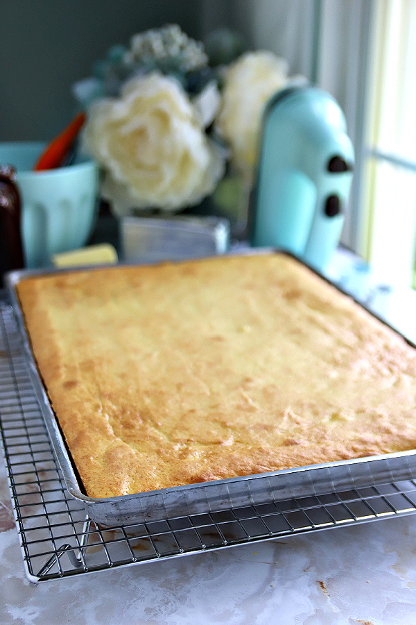 Just out of the oven lemon sheet cake cooling on a rack.