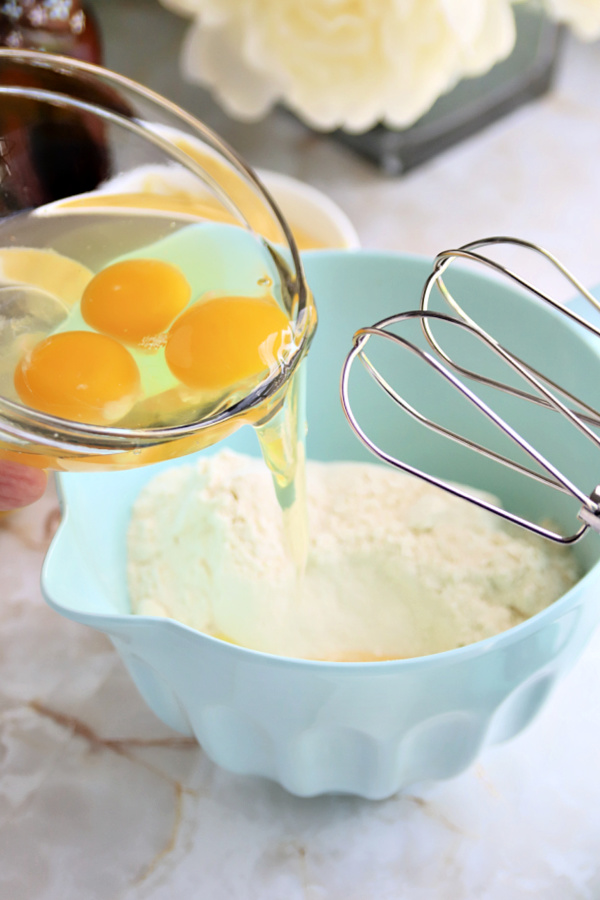 Adding eggs to the cake mix for lemon sheet cake with cream cheese frosting.